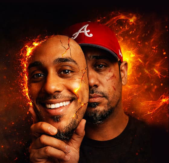 Man holding cracked smiling mask surrounded by fire